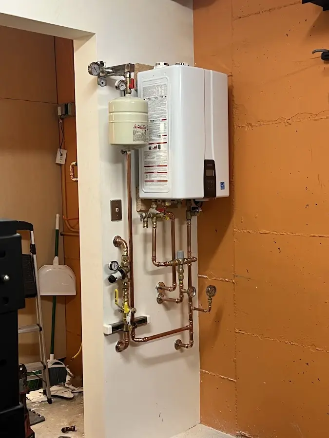 Plumbing technician inspecting water heater connections in East Donegal